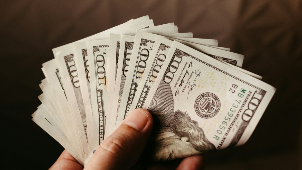Hand holding 100 dollar bills